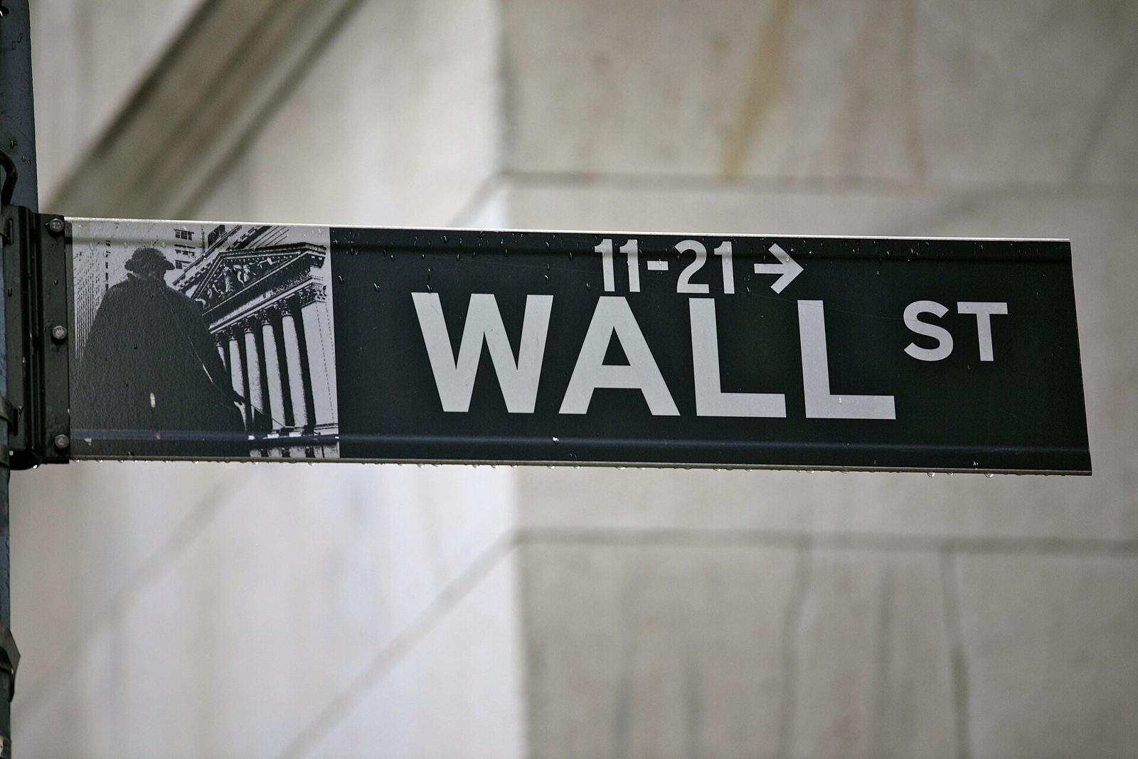A black Wall St street sign against a stone building