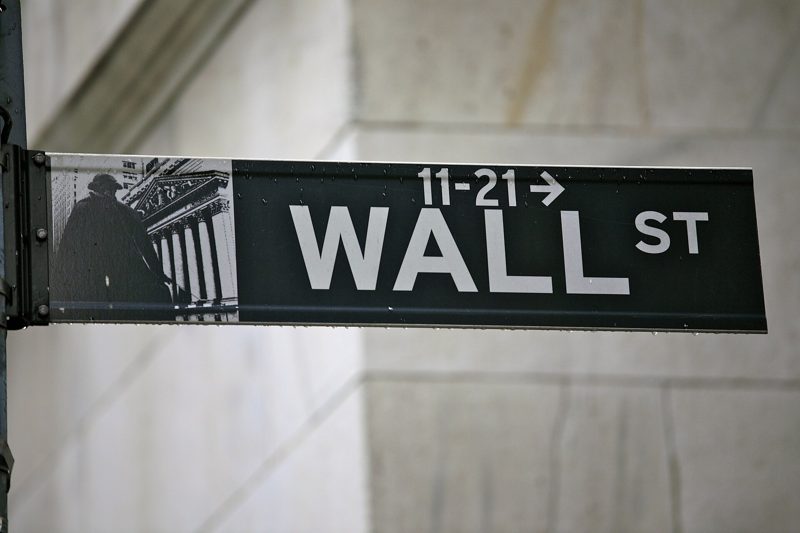A black Wall St street sign against a stone building