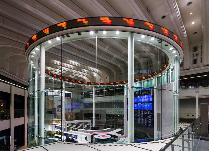 A glass cylinder ringed by a scrolling stock ticker inside the Tokyo Stock Exchange