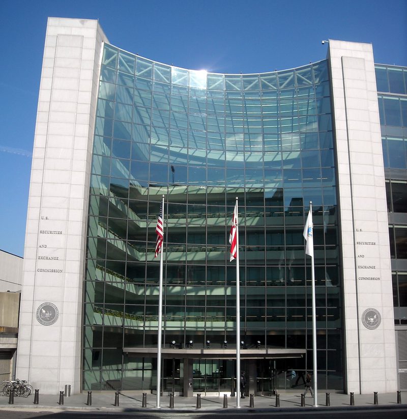 The curved glass entrance of the SEC headquarters with flags